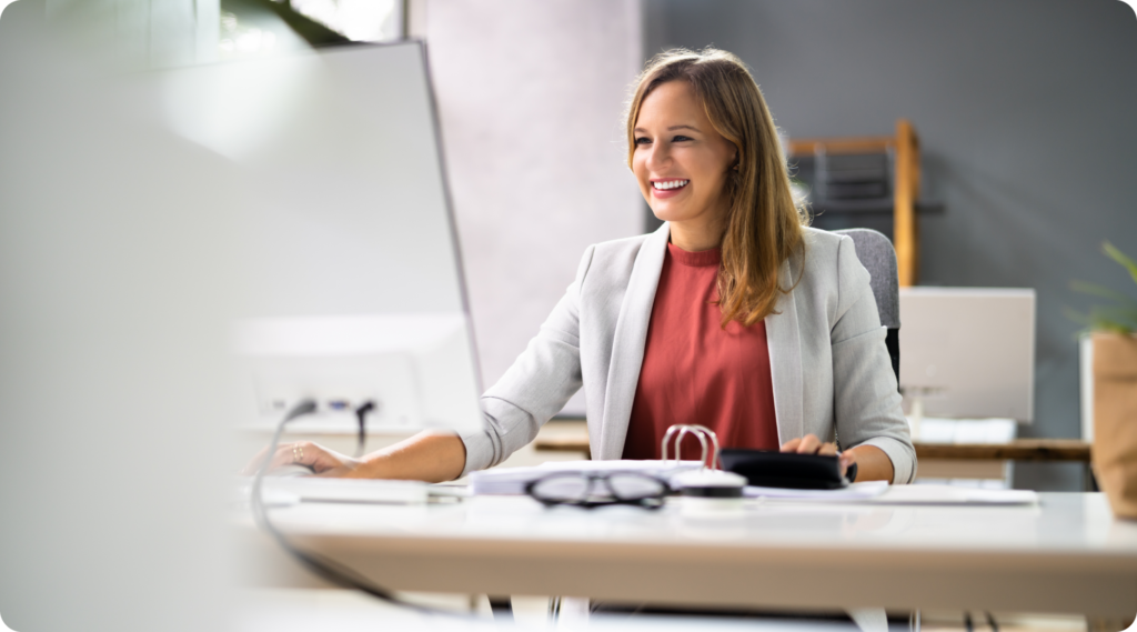 Woman at a desk smiling at her computer.